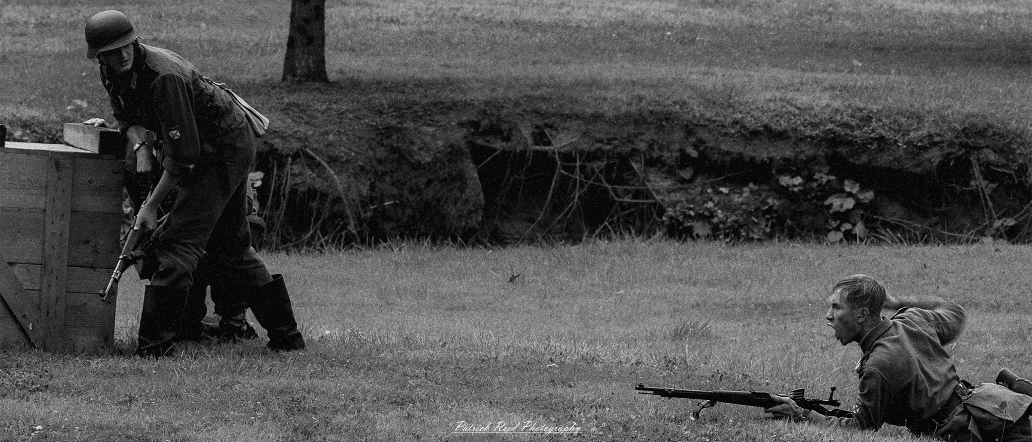 A soldier lying in the grass, his face contorted in a scream as he calls out to his comrades. The scene captures the urgency and desperation of the moment, highlighting the intense emotions experienced in the heat of battle.